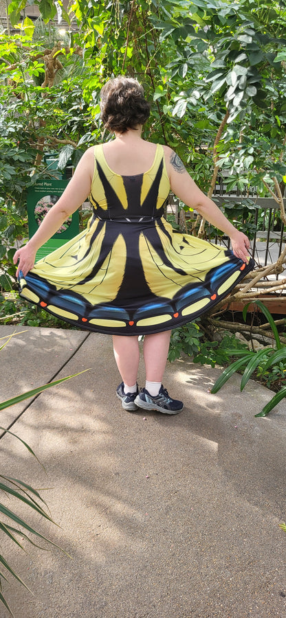 Person holding a tiger swallowtail dress in a natural setting with greenery.